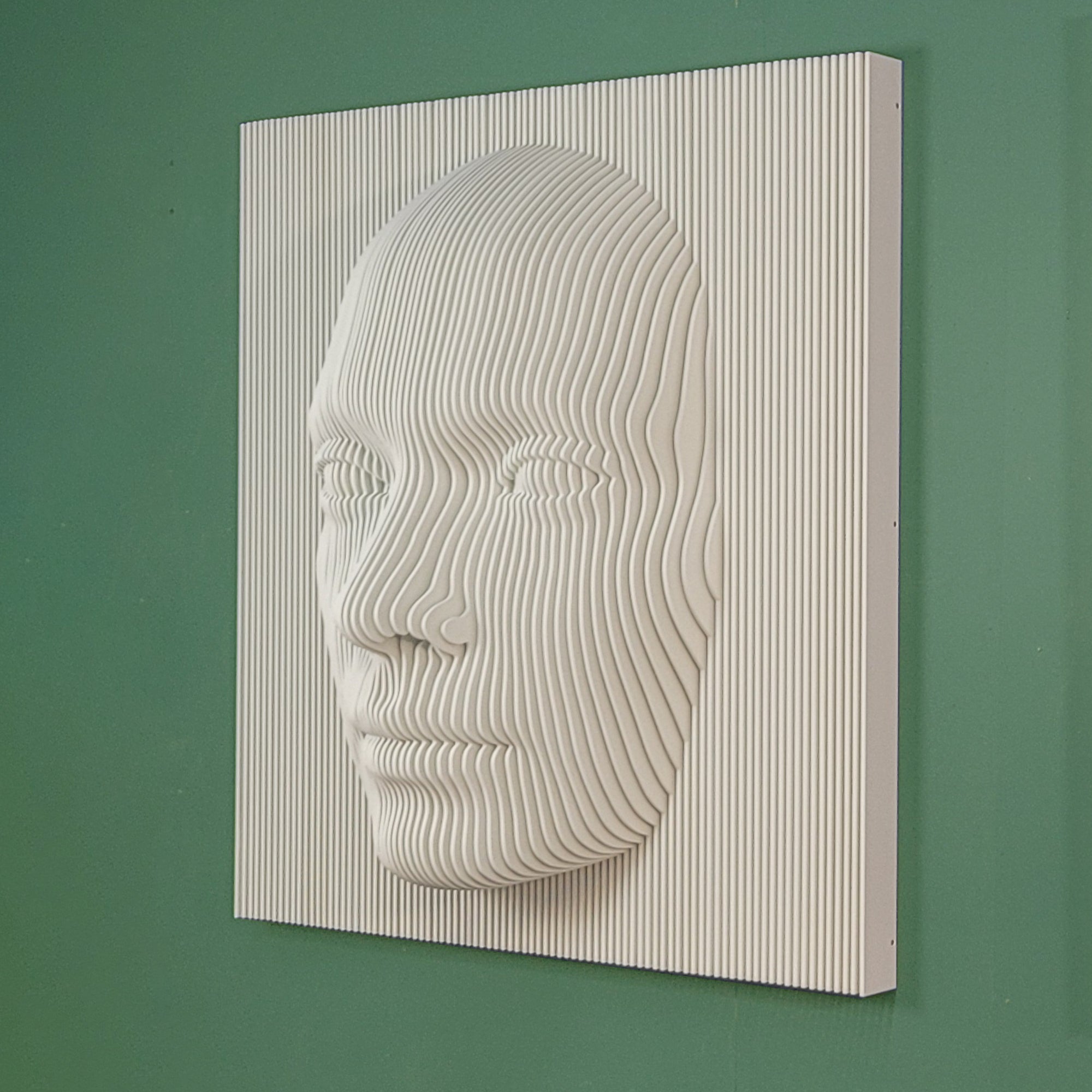 A three-dimensional wall sculpture of a human face with vertical lines, installed on a wall in a room with a window and a lamp.